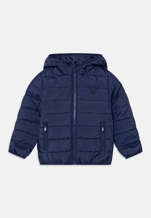 Veste matelassée pour enfants bleu marine avec capuche, fermeture éclair à l'avant, deux poches zippées et un petit patch triangulaire sur la poitrine.
