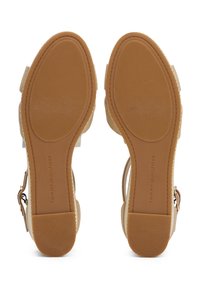 Paire de sandales beiges pour femmes avec semelles marron texturées, petits talons blocs et brides latérales ajustables.