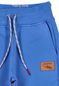Blauwe katoenen sweatpants met een gestructureerde tailleband, grijze strikbanden met rode accenten en een leren label met de opdruk "Lagarto Verde."