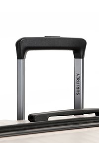 Manico della valigia espandibile in argento con impugnatura nera e zip visibile, marchiato "SURIFREY" su un lato.