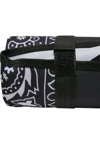 Sort stofrulle med hvidt indviklet mønster, sikret med et sort spændebånd og velcro. Glat tekstur, rektangulær form, kompakt design.
