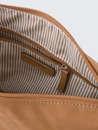 Tan synthetic handbag interior with vertical beige and brown stripes, featuring zip compartments and a branded leather tag.