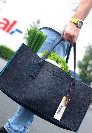 Gray felt tote bag with blue trim, two handles, holding green onions and lettuce. Tag attached, rectangular shape, durable material.