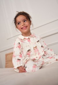 Ensemble de pyjama blanc avec des illustrations de danseuses de ballet en rose. Tissu doux avec un col et un design boutonné à l'avant, manches longues.