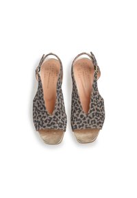 Sandal bertakung dengan corak harimau mempunyai atas suede lembut berwarna kelabu dan hitam, bukaan jari kaki, dan tumit wedge yang diserlahkan dengan aksen emas.