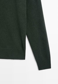 Donkergroene gebreide trui met lange mouwen, een gladde textuur, ribgebreide manchetten en zoom, met een relaxte snit en taps toelopende pasvorm.