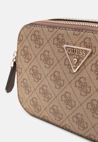 Borsa sintetica marrone con cerniera e motivo a diamante, con logo triangolare dorato sulla parte anteriore e cursore della cerniera laterale.