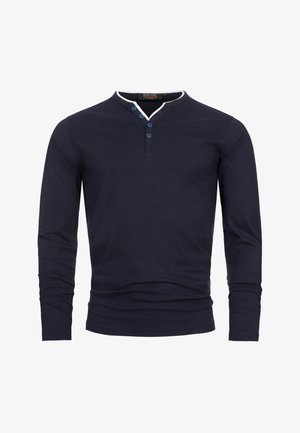 Tmavě modré tričko s dlouhým rukávem z bavlny, s výstřihem Henley se třemi modrými knoflíky a bílým lemováním límce. Minimalistický design.