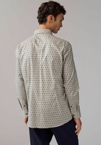 Helles graues Hemd mit schwarzen Punkten, ausgestattet mit einem Button-Down-Kragen und langen Ärmeln. Glattes Material mit normaler Passform.