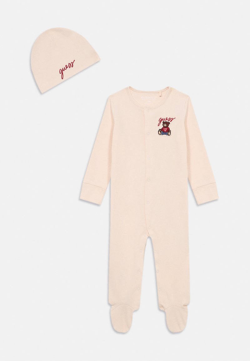 Body per neonato in morbido tessuto rosa con maniche lunghe, con bottoni a pressione, design con i piedi; include un berretto coordinato rosa con ricamo rosso "guess".