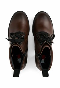 Bottines en cuir marron avec des lacets noirs, bout rond, zips sur le côté et languettes de tirage. L'intérieur dispose d'une semelle interne griffée et d'un intérieur doux.