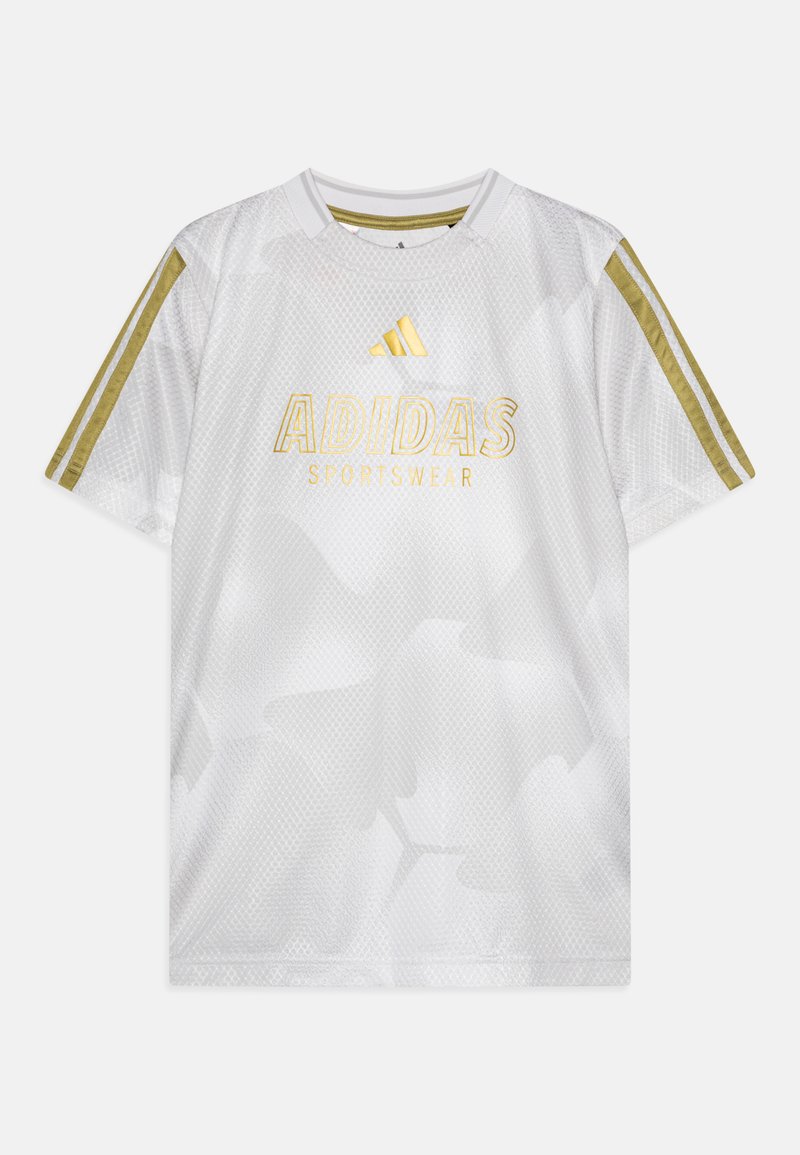 Balts adidas sporta krekls ar sešstūrveida rakstu, zelta akcentiem un trim zelta svītrām uz katras pleca. Uz krekla ir norakstīts "ADIDAS SPORTSWEAR" zelta krāsā.