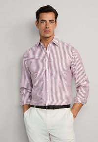 Pánská košile na knoflíky v bílých a červených vertikálních pruzích, vyrobena z bavlny, s dlouhými rukávy, které jsou na manžetách ohrnuté a s klasickým límcem.