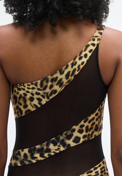 Ολόσωμο μαγιό με ένα ώμο, με μαύρο διαφανές ύφασμα και λεοπάρ λεπτομέρειες, που τονίζει τις καμπύλες με έντονα μοτίβα και αντιθετικές υφές.