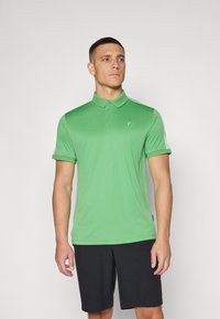 Grøn poloshirt i et glat, let stof med krave og tre-knaps placket. Korte ærmer, parret med sorte shorts.