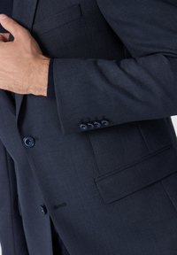 Navy strukturierter Blazer im Slim-Fit. Verfügt über eine Brusttasche, zwei Knöpfe und geknöpfte Ärmelabschlüsse. Das Material scheint gewebt zu sein.