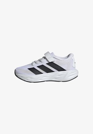 Zapatilla deportiva blanca con rayas negras, diseño de cordones y una tira de velcro encima, mostrada sobre un fondo blanco.