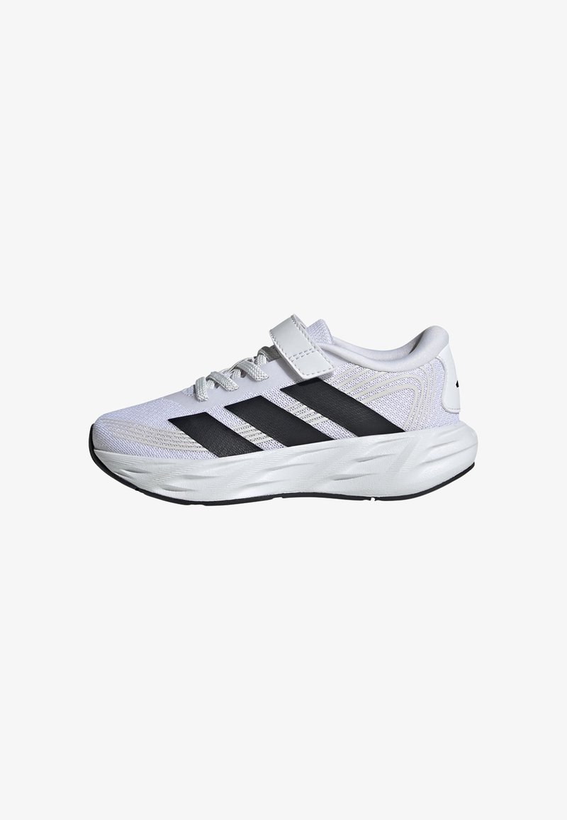 Chaussure de sport blanche avec des bandes noires, design à lacets et une bride velcro sur le dessus, présentée sur un fond blanc.