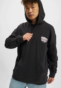 Black hooded sweatshirt with a front pocket, featuring pink retro text "REMIXED." Made from soft material with long sleeves and a relaxed fit.