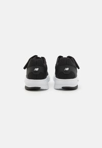 Chaussures de sport noires avec une tige en mesh et synthétique, semelle intermédiaire blanche et semelle extérieure noire. Les caractéristiques incluent une sangle à crochets et boucles et un accent de logo.
