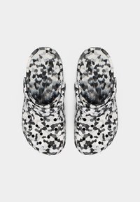 Τσόκαρα με λουράκια στο πίσω μέρος, με αφηρημένο καμουφλάζ σε μαύρο, λευκό και γκρι χρώμα, και οπές εξαερισμού στο επάνω μέρος.