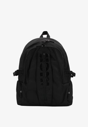 Sac à dos noir en tissu durable avec une forme arrondie, comprenant une poche zippée à l'avant, des poches latérales et un accent de logo.