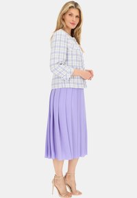 Jasnoniebieska i biała krótka kurtka w kratkę z postrzępionymi brzegami, zestawiona z plisowaną lawendową midi spódnicą i beżowymi szpilkami z paskiem na kostce.