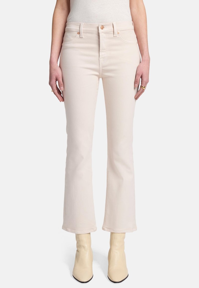 Jean évasé rose clair avec une taille haute, fabriqué en denim avec une texture lisse, comportant un bouton doré et des poches avant.