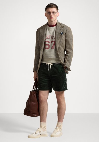 Sacou cu model houndstooth, hanorac gri cu litere roșii, pantaloni scurți din corduroy verzi, adidași crem, șosete bej și geantă din piele maro.