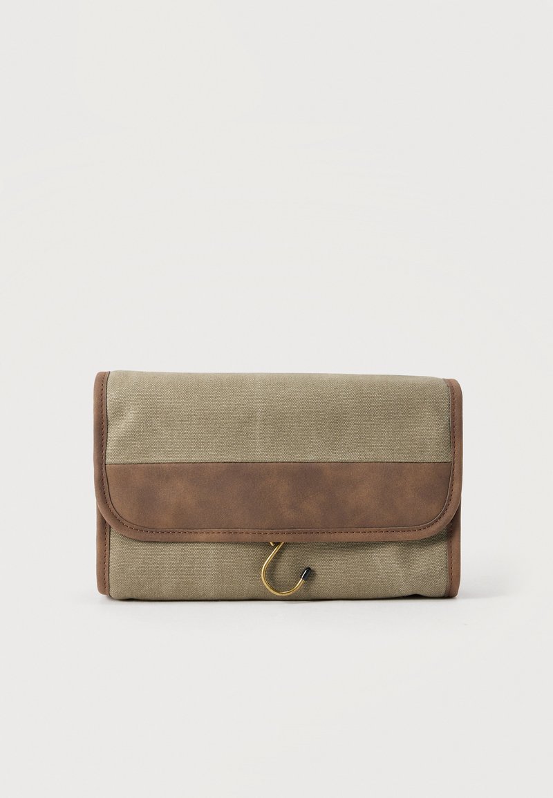 Μικρή ορθογώνια τσαντάκι ταξιδιού για αξεσουάρ καλλωπισμού από μπεζ καμβά και καφέ δέρμα με κλείσιμο χρυσού γάντζου σε λευκό φόντο.