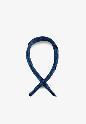 Sininen ja musta paisley-kuvioitu solmio, joka on solmittu löyhäksi silmukaksi valkoisella taustalla.