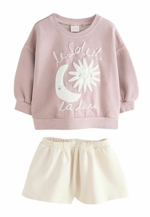 Bluza roz roz cu mâneci lungi, cu fețe de soare și lună și textul „le soleil la lune”, asortată cu pantaloni scurți cu talie elastică de culoare crem.