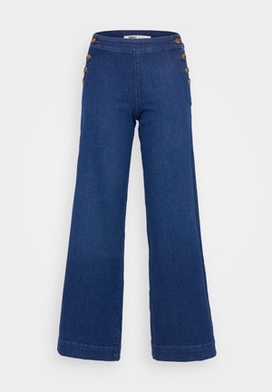 Dark blue flared jeans made of denim. High waist with six large brown buttons on the side and neat stitching along the hems.