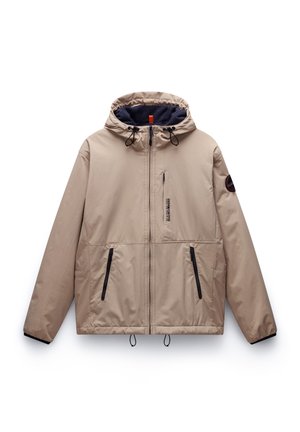 Veste à capuche beige avec un extérieur lisse, doublure bleu marine, accents noirs, deux poches zippées à l'avant et cordons de serrage à l'ourlet et à la capuche.