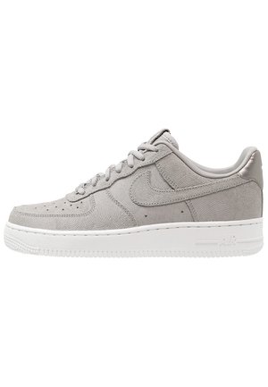 Szary niski sneaker z teksturowanym wzorem spirali, sznurowany z przodu, biała podeszwa oraz subtelne logo Swoosh po boku.