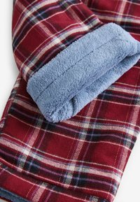 Rot und blau kariertes Gewebe mit einem weichen blauen Fleecebund. Das Muster beinhaltet dünne weiße und schwarze Linien. Das Material wirkt warm und strukturreich.