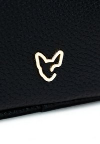 Un materiale nero texturizzato presenta un emblema di volpe dorato, offrendo un design elegante con contorni definiti e una finitura lucida.