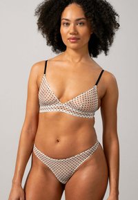 Leicht gepolsterter Bralette und passender String aus durchscheinendem, nude-farbenem Stoff mit schwarzen Polka-Dots. Verfügt über dünne schwarze Träger und eine glatte Oberfläche.