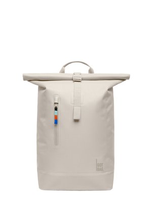 Jasnobeżowy plecak z zamknięciem na zwijaną klapę, z przednią pionową kieszenią na suwak z kolorową zawieszką oraz logo "GOT BAG" w dolnym prawym rogu.