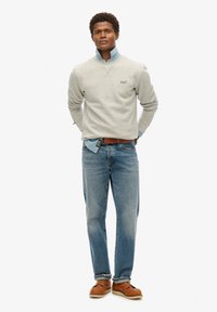 Grå pullovertrøje med krave, lagd over en lyseblå denimskjorte, parret med blå jeans og brune sko. Enkel, afslappet design.