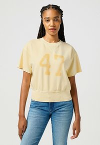 Felpa gialla a maniche corte con un fit morbido, caratterizzata da un grande logo testurizzato "47" sul davanti e un orlo a costine.