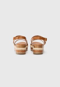 Barna bőr platform szandál, bokapánttal, texturált raffia talppal és szőtt részletekkel a talp szélén.