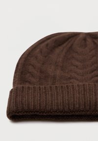 Beanie marrone in lana lavorata a maglia con risvolto a coste e motivo a chevron testurizzato su uno sfondo bianco semplice.