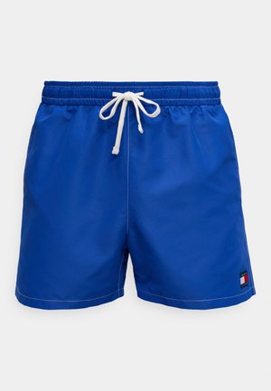 Blå badeshorts med elastisk midje, hvit snor og kontrasterende søm. Har en liten logo på nederste side.