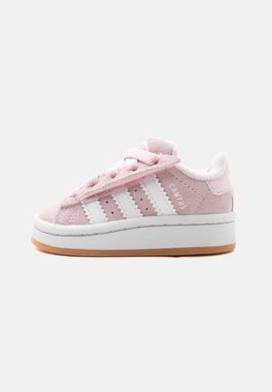 Baskets en daim rose avec des rayures blanches, semelle blanche épaisse, bride velcro et lacets roses, vues de profil sur fond blanc.