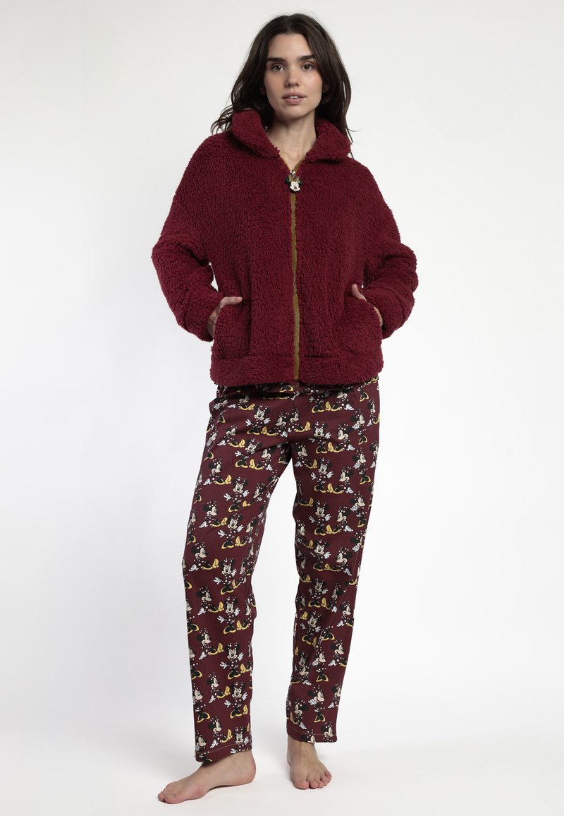 Chaqueta de forro polar burdeos con capucha y cremallera dorada, combinada con pantalones de pijama color marrón claro que presentan un estampado de animales de dibujos animados.