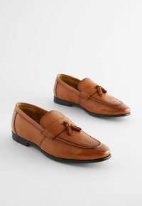 Mocassins en cuir brun avec une bande texturée et un accent à pompon. Fini lisse, bout arrondi, petit talon et couture contrastante.