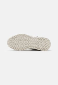 Podešev tenisky s texturovaným vzorem obsahujícím diamantové tvary. Barva je světle krémová s matným povrchem, navržena pro přilnavost.