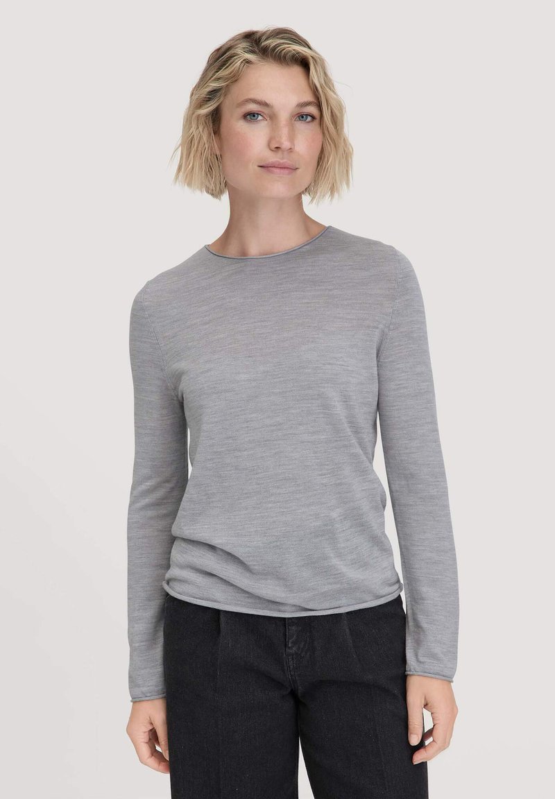 Lichtgrijze lange mouw shirt met een ronde hals, gemaakt van zachte stof, met een ontspannen pasvorm en subtiele textuur. Gepaard met donkere broek.