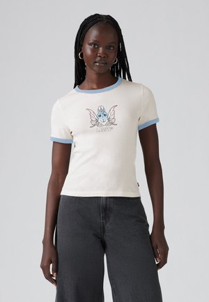 Ljusbeige t-shirt med kort ärm, blå ribbad krage och mudd, med en färgglad grafisk design på framsidan. Matchas med mörka jeans.